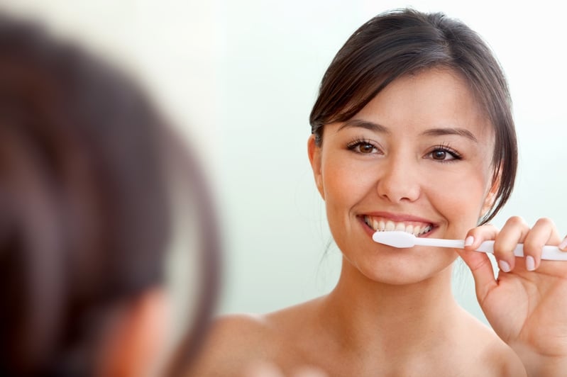 Woman in front of a mirror brushing her teeth